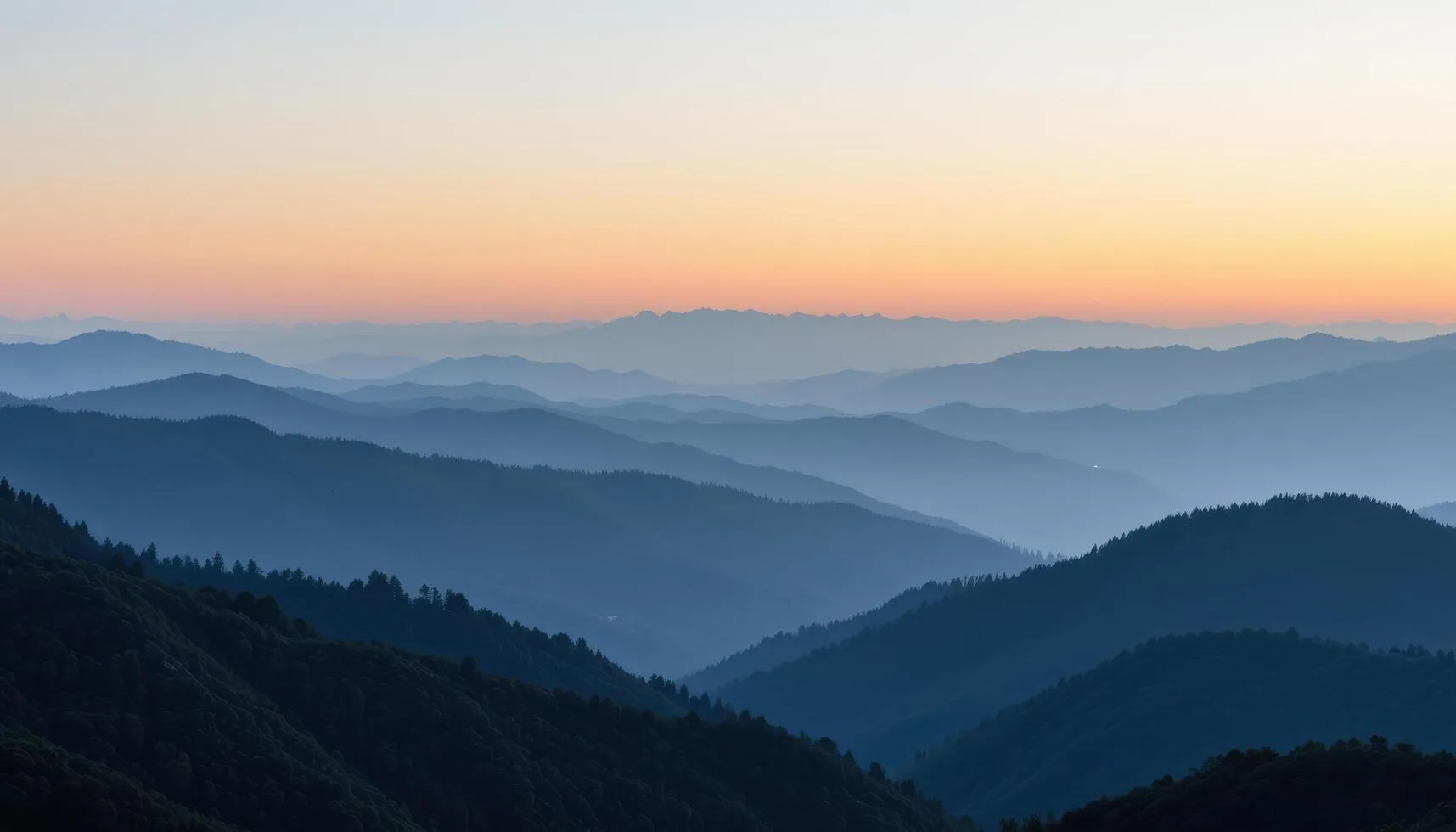 Layered misty forest landscape with soft green hills fading into morning haze